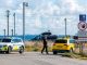 A police officer walks near a police car and a yellow vehicle by a restricted area sign after drones were observed in Danish airspace.