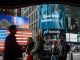 People walk past electronic billboards displaying the Nasdaq logo in New York.