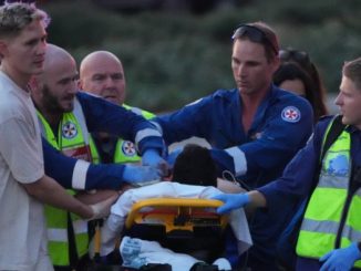 Emergency workers and paramedics transport a person on a stretcher, attending to injuries after a reported shooting.