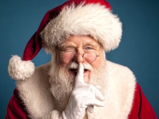 Studio image of Santa Claus Smiling, winking, and placing his finger in front of his lips.