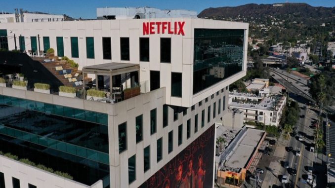 Netflix logo atop Sunset Bronson Studios office building with the Hollywood sign visible in the distant hills.