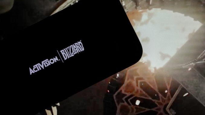 logo of ''Activision Blizzard'' is displayed on a mobile phone screen in front of a computer