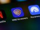 A smartphone screen displays app icons for Netflix, Warner Brothers Discovery, and Paramount Plus.
