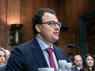 Anthropic CEO Dario Amodei sitting at a table and speaking into a microphone during a Senate committee hearing.