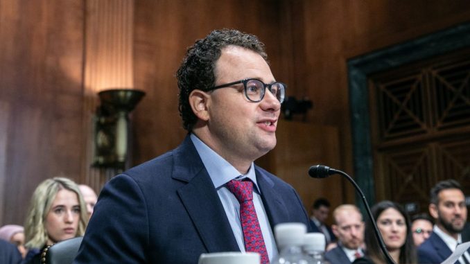 Anthropic CEO Dario Amodei sitting at a table and speaking into a microphone during a Senate committee hearing.