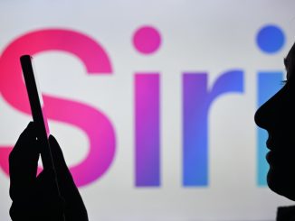An image of a woman holding a cell phone in front of the Siri logo displayed on a computer screen.