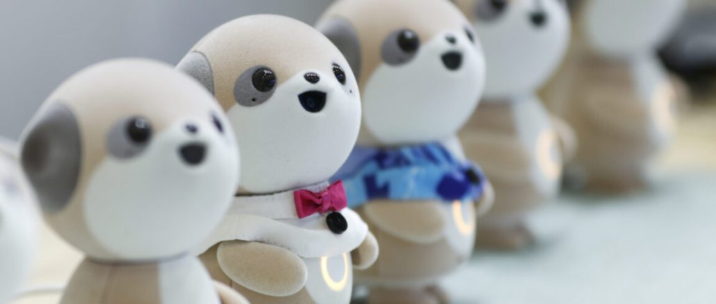 Four plastic anthropomorphic toy dogs are lined up on display at a trade show.
