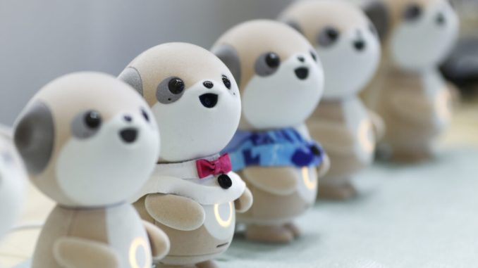 Four plastic anthropomorphic toy dogs are lined up on display at a trade show.