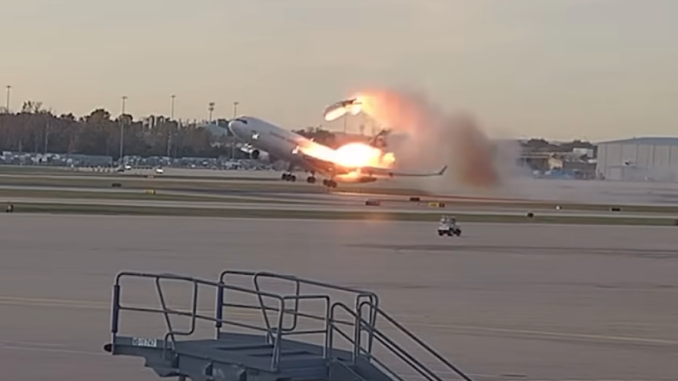 Still image from a video showing a cargo plane taking off while fire engulfs a wing and the left engine having detached. The crash of UPS flight 2976 killed three pilots aboard the aircraft and killed a dozen more people on the ground, with 23 people being injured.