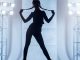 Beautiful slim young woman with two braids dressed in a black clinging clothes. The young woman dancer is performing the dance in the vogue style. She is standing holding the braids in hand. Studio shooting on a white background with light blue backlighting on a two stands