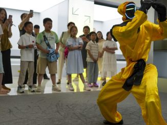 Children watch a martial arts performance by Unitree robots at a humanoid robot store on June 1, 2026 in Zhengzhou, Henan Province of China. The robot is wearing yellow martial arts clothing.