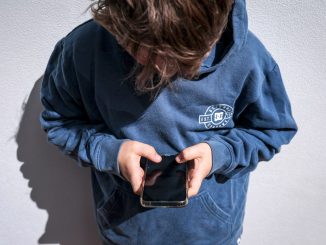 Shows a 14-year-old boy as he looks at social media on his mobile phone.