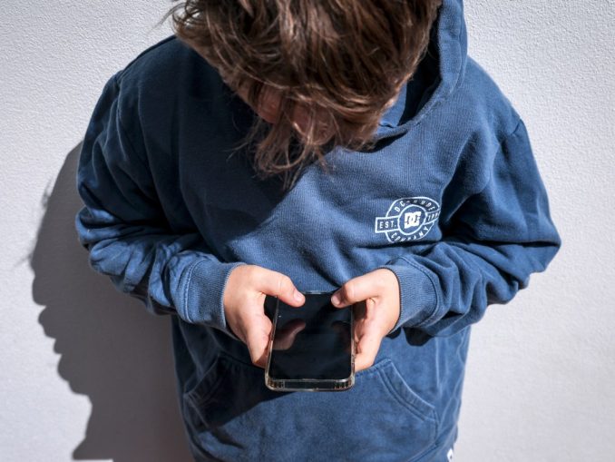 Shows a 14-year-old boy as he looks at social media on his mobile phone.