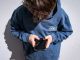 Shows a 14-year-old boy as he looks at social media on his mobile phone.