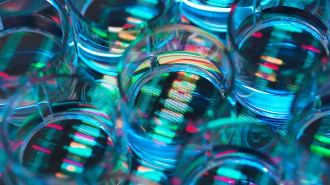 A human sample in a multi well plate ready for genetic analysis with a DNA sequence in the background
