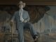 elderly man in a light blue suit and cowboy hat and boots holding a shovel